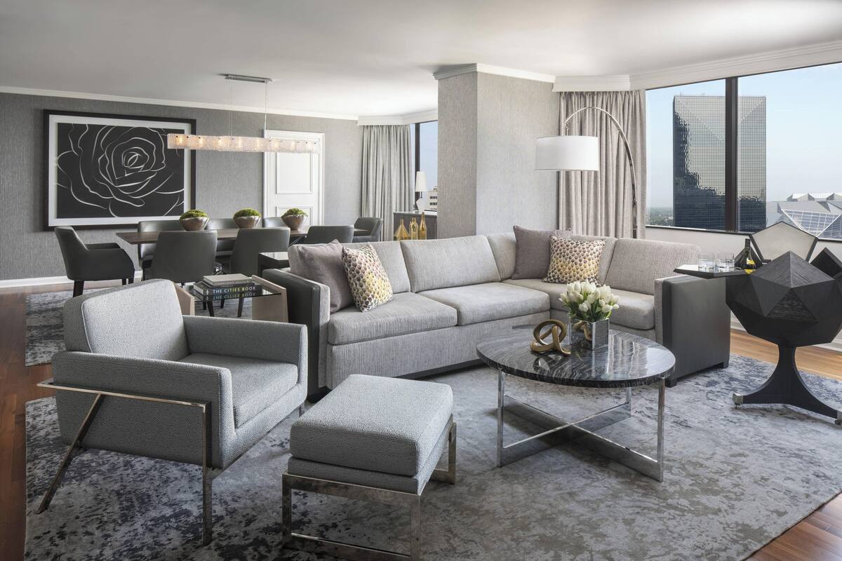 A modern living room with a grey sofa, armchairs, and a coffee table.