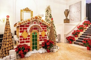 A grand hall with a Christmas-themed display including a gingerbread house, poinsettias, and a staircase. - The Ritz-Carlton, Atlanta (Atlanta)