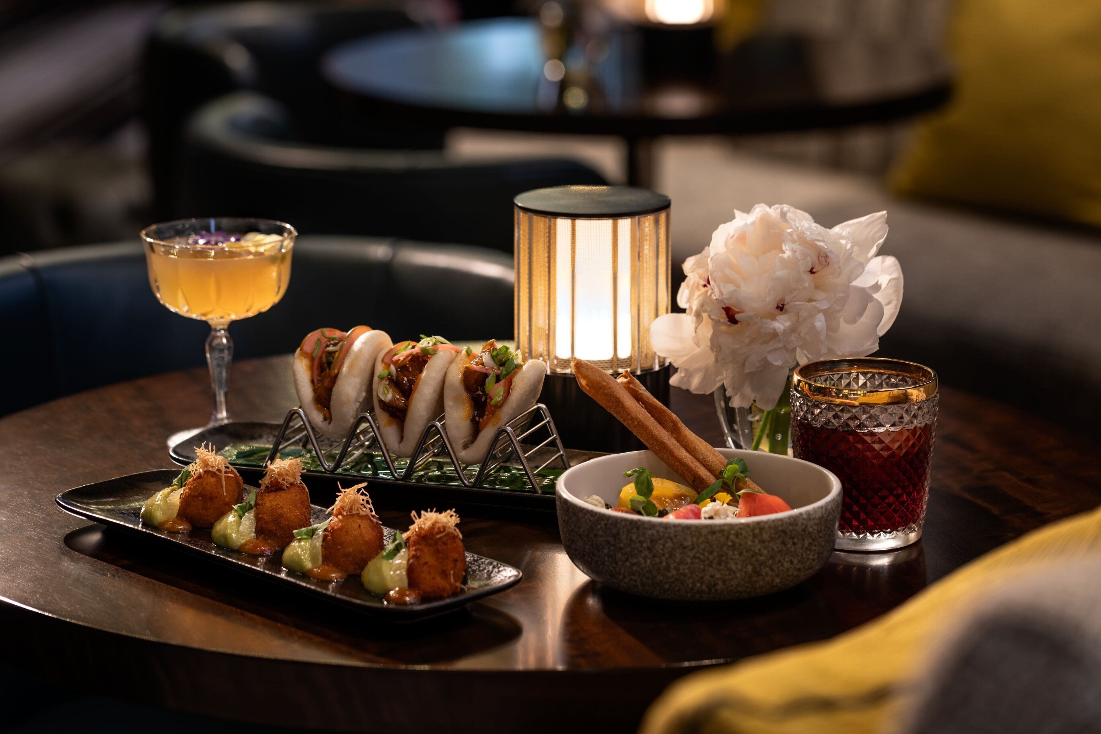 A dining table with a variety of dishes, a candle, and a glass of drink.