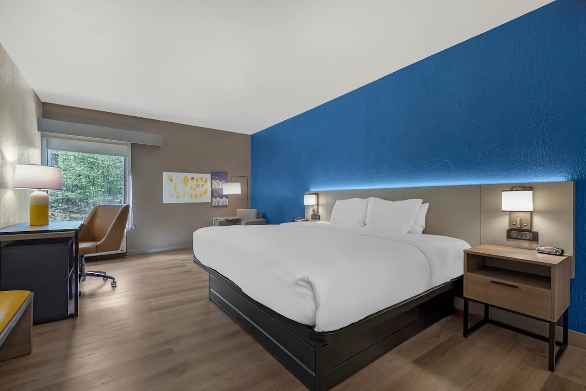 Una habitación de hotel moderna con una cama grande, mesitas de noche, un escritorio y una silla.