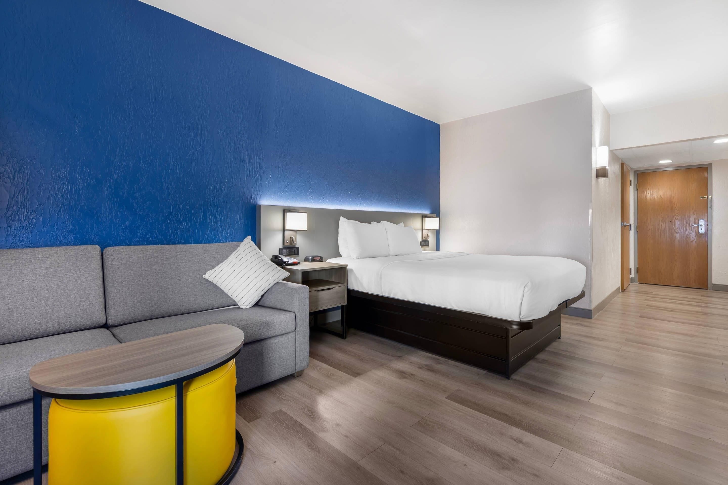 Habitación de hotel con cama, sofá, una mesita, una mesita de noche y una lámpara.