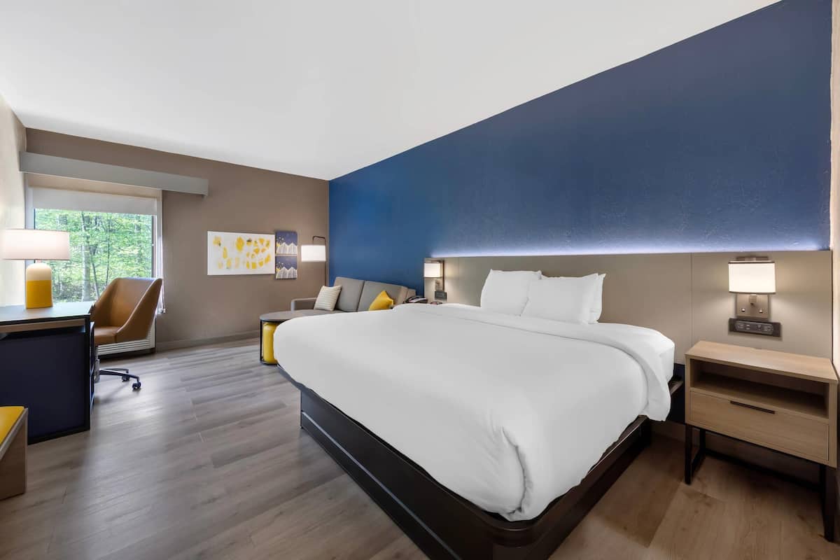 Una habitación de hotel moderna con una cama grande, mesitas de noche, un escritorio y una silla.