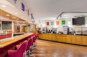 Una zona de bar con mostrador, taburetes rojos y una pizarra de menú.