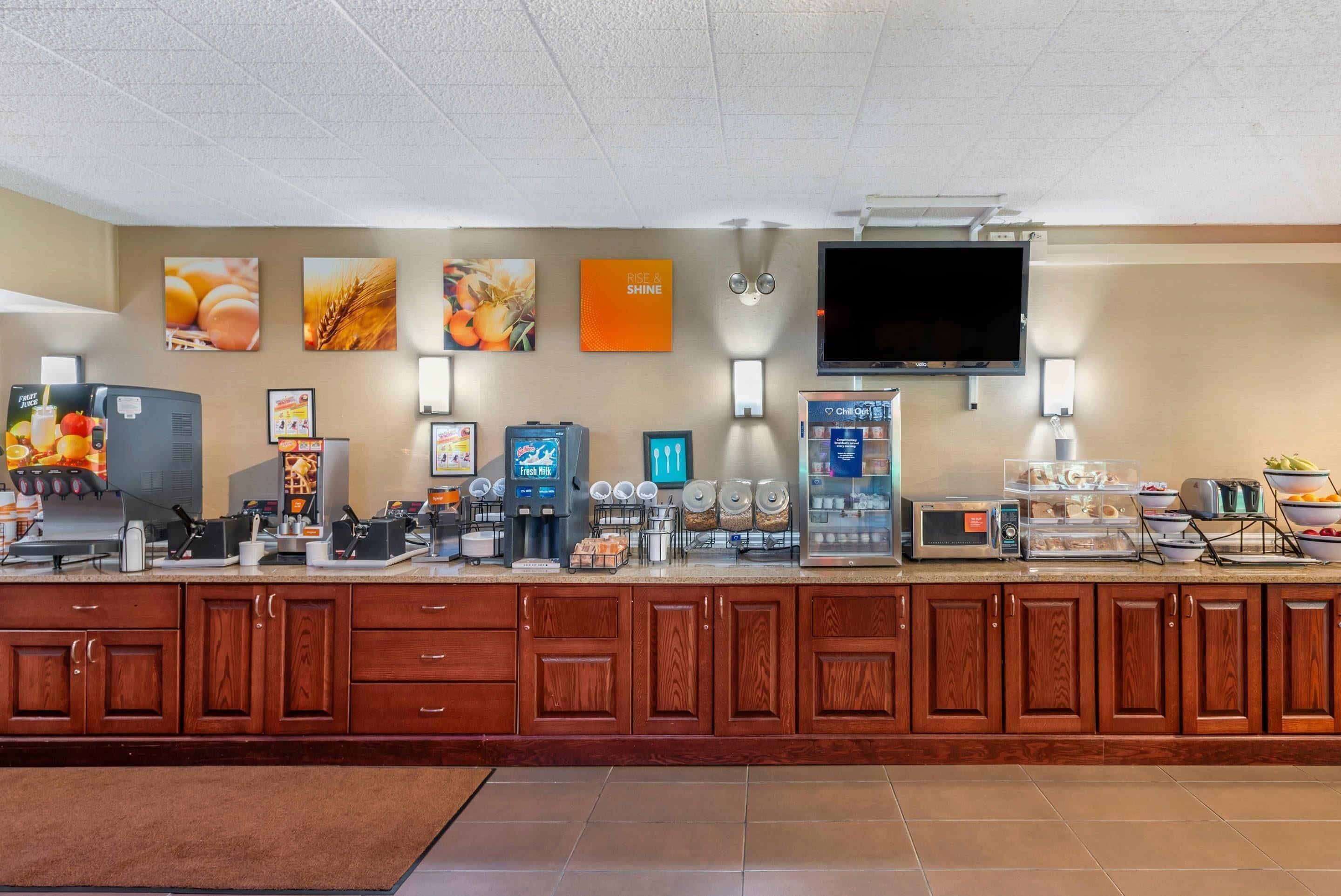 A breakfast bar with coffee machines, a TV, and various food items.