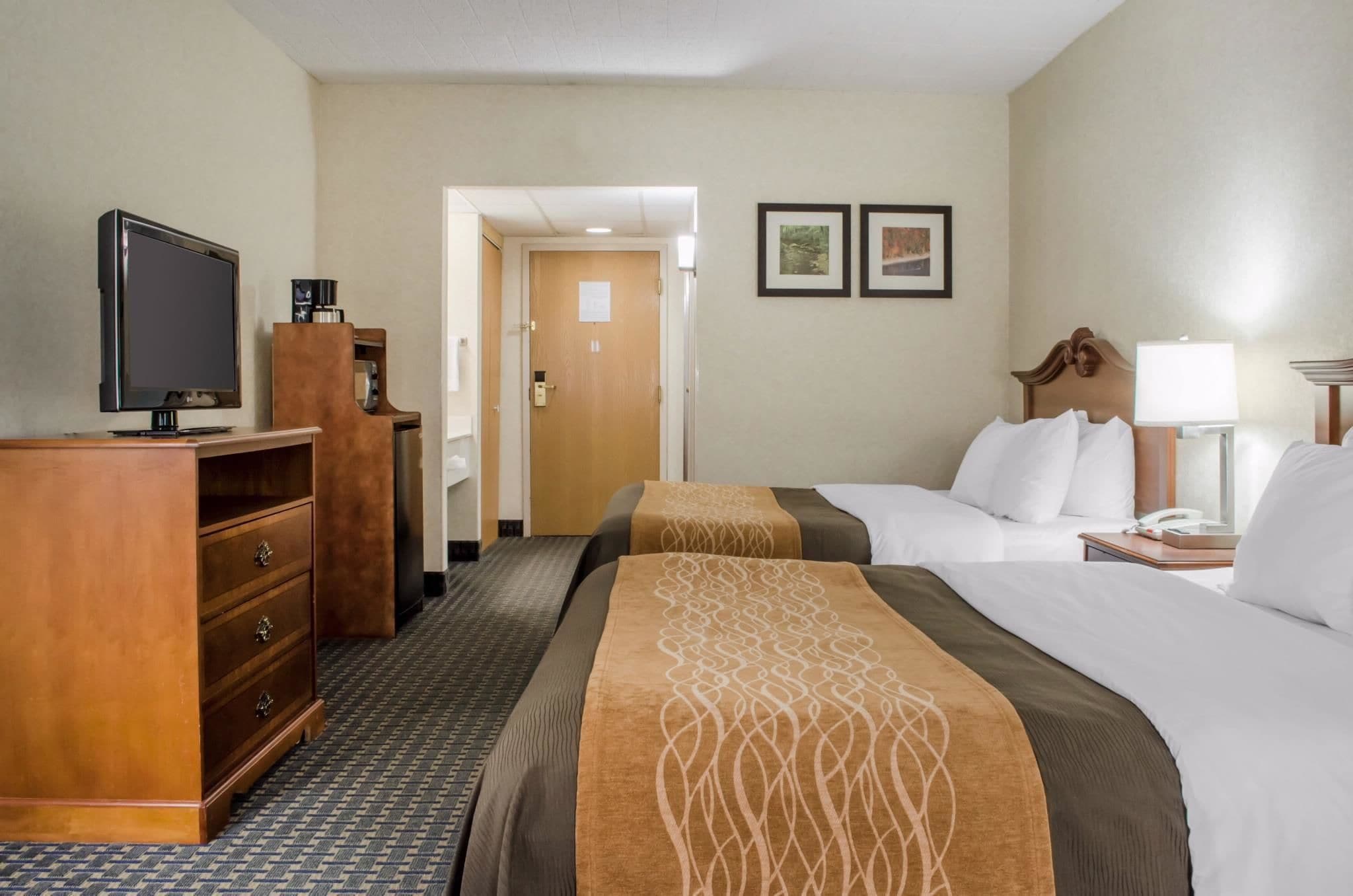 Ein Hotelzimmer mit zwei Betten, einem Fernseher, einem Schreibtisch und einem Schminktisch.
