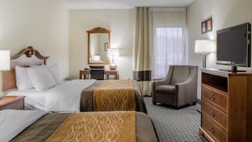 A hotel room with two beds, a desk, a chair, a television, and a dresser.