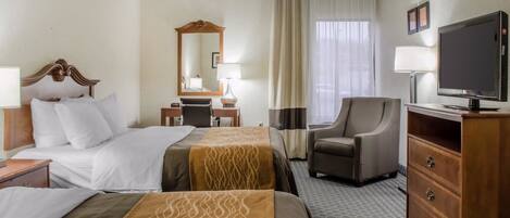 A hotel room with two beds, a desk, a chair, a television, and a dresser.