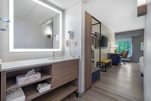 Un baño moderno con un espejo grande, un lavabo y un mueble de tocador con espacio de almacenamiento.