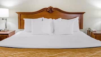 Una cama bien hecha con sábanas blancas, cabecera de madera y edredón estampado.