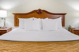 Una cama bien hecha con sábanas blancas, cabecera de madera y edredón estampado.