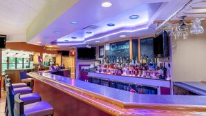Un espace bar avec un comptoir, des tabourets et une variété de bouteilles.