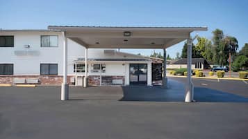 Un motel doté d’un parking couvert, d’un petit bâtiment avec une fenêtre et d’un mur en briques.