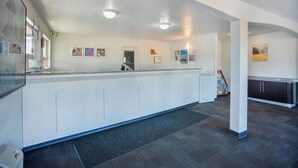 A spacious reception area with a long counter, a small staircase, and a display of local products. - Motel 6 Gresham, OR - Portland (Gresham)