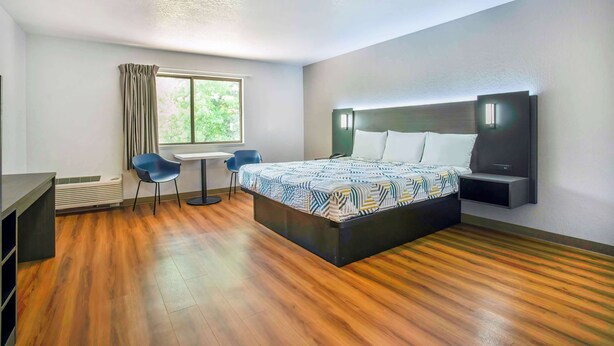 A modern hotel room with a large bed, a desk, and a chair. - Motel 6 Gresham, OR - Portland (Gresham)