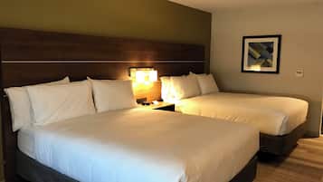 A hotel room with two beds, a nightstand with a lamp, and a framed picture on the wall.