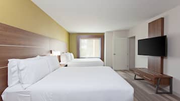 Ein Hotelzimmer mit zwei Betten, einem Fernseher, einem Schreibtisch und einem Fenster.