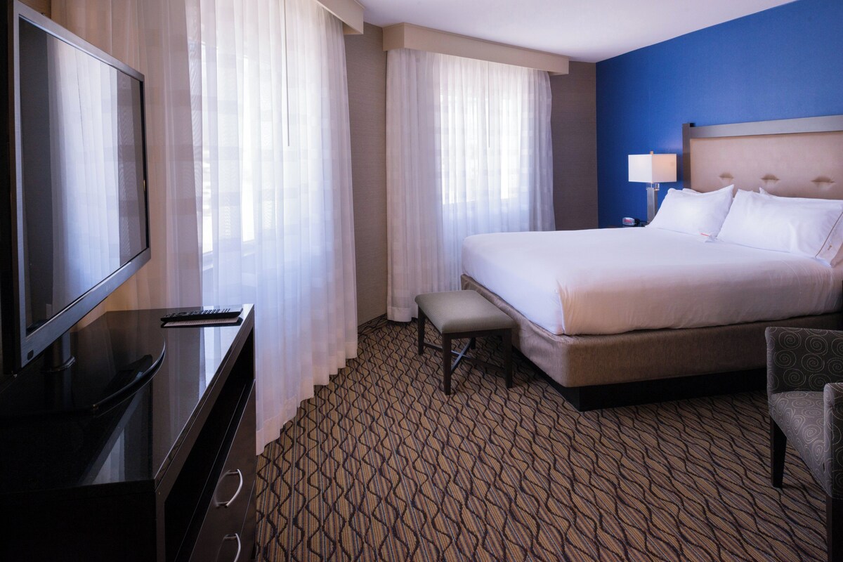 A hotel room with a bed, a television, a desk, and a chair.
