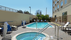 A pool area with two pools, lounge chairs, and a lifeguard stand.