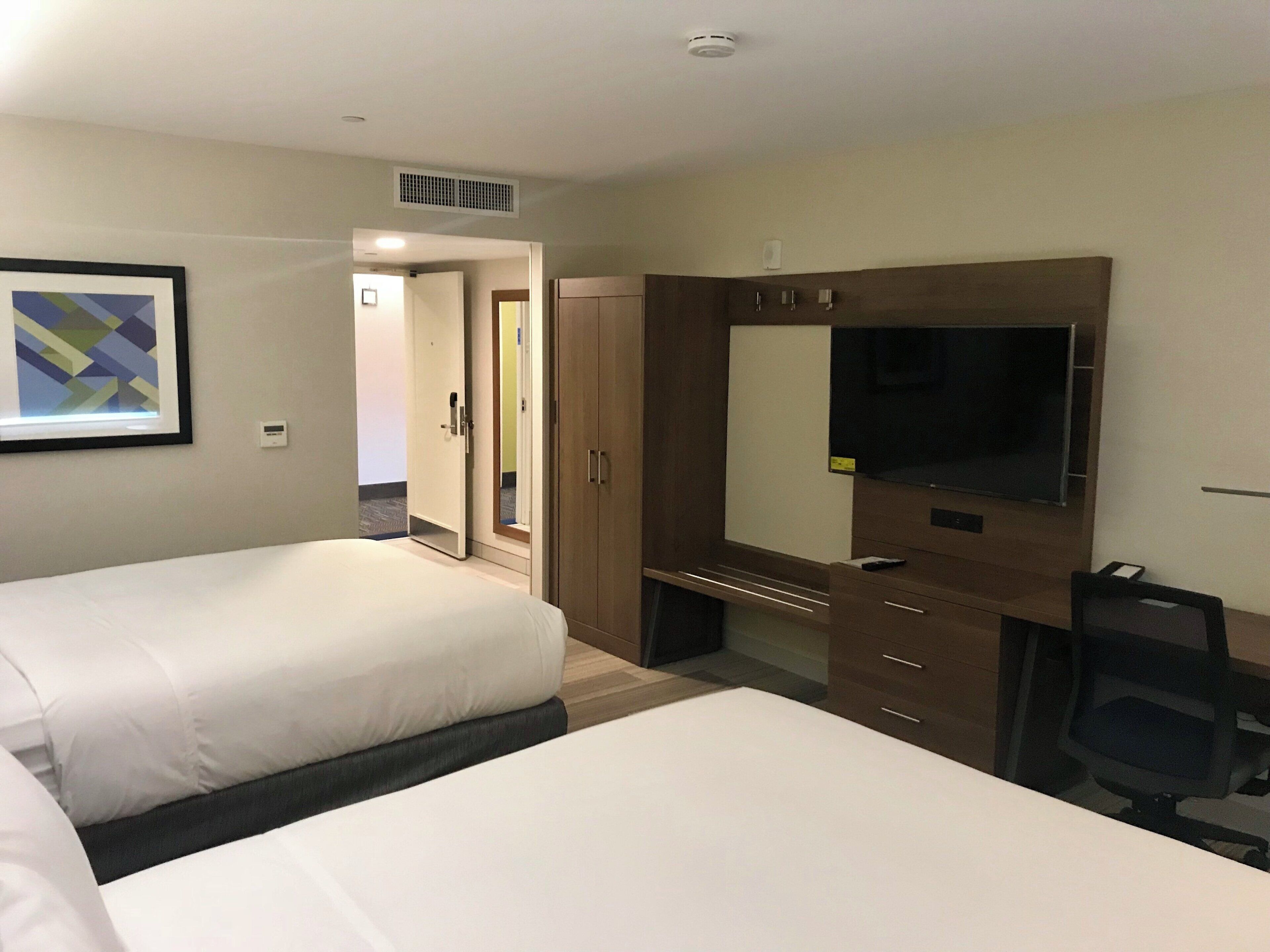 Een hotelkamer met twee bedden, een bureau, een televisie en een spiegel.