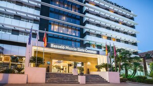 Un hotel moderno con varios pisos, una entrada destacada y banderas.