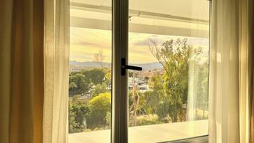 A window with a view of a cityscape, including buildings and trees.