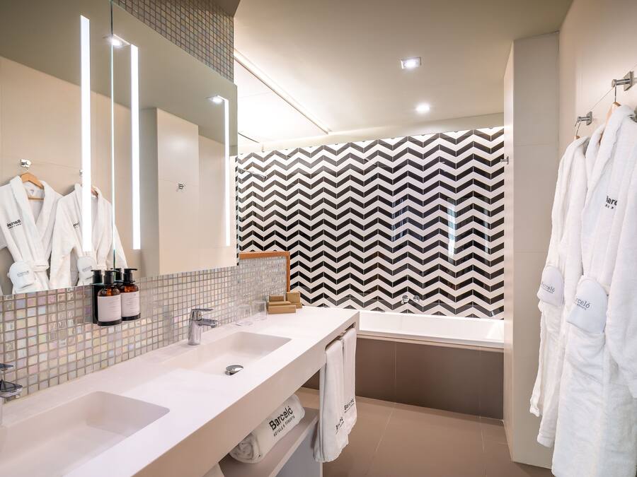 A modern bathroom with two sinks, a large mirror, and a black and white chevron-patterned wall.