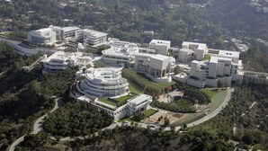 Vista aérea de un moderno complejo arquitectónico con varios edificios, zonas verdes y caminos sinuosos.