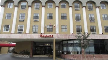 Un bâtiment à la façade jaune, doté de nombreuses fenêtres et d’une enseigne indiquant « RAMADA ».
