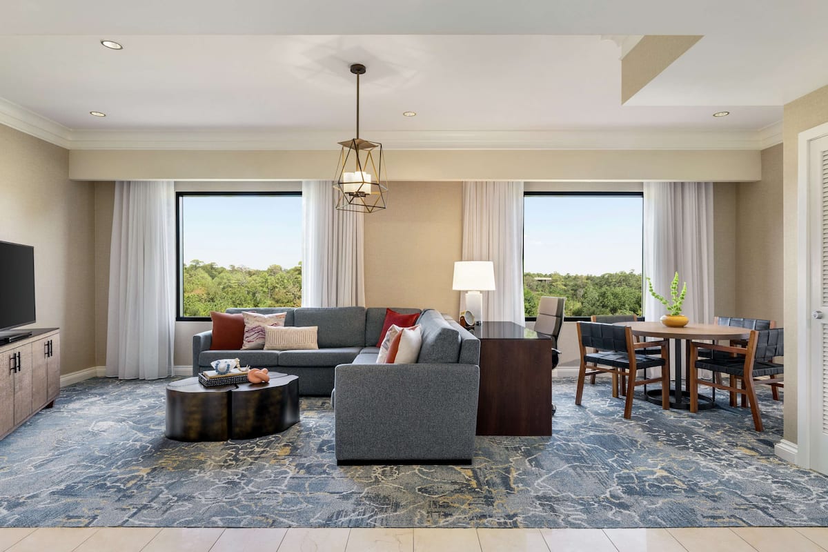 A modern living room with a sofa, coffee table, TV, and dining area.
