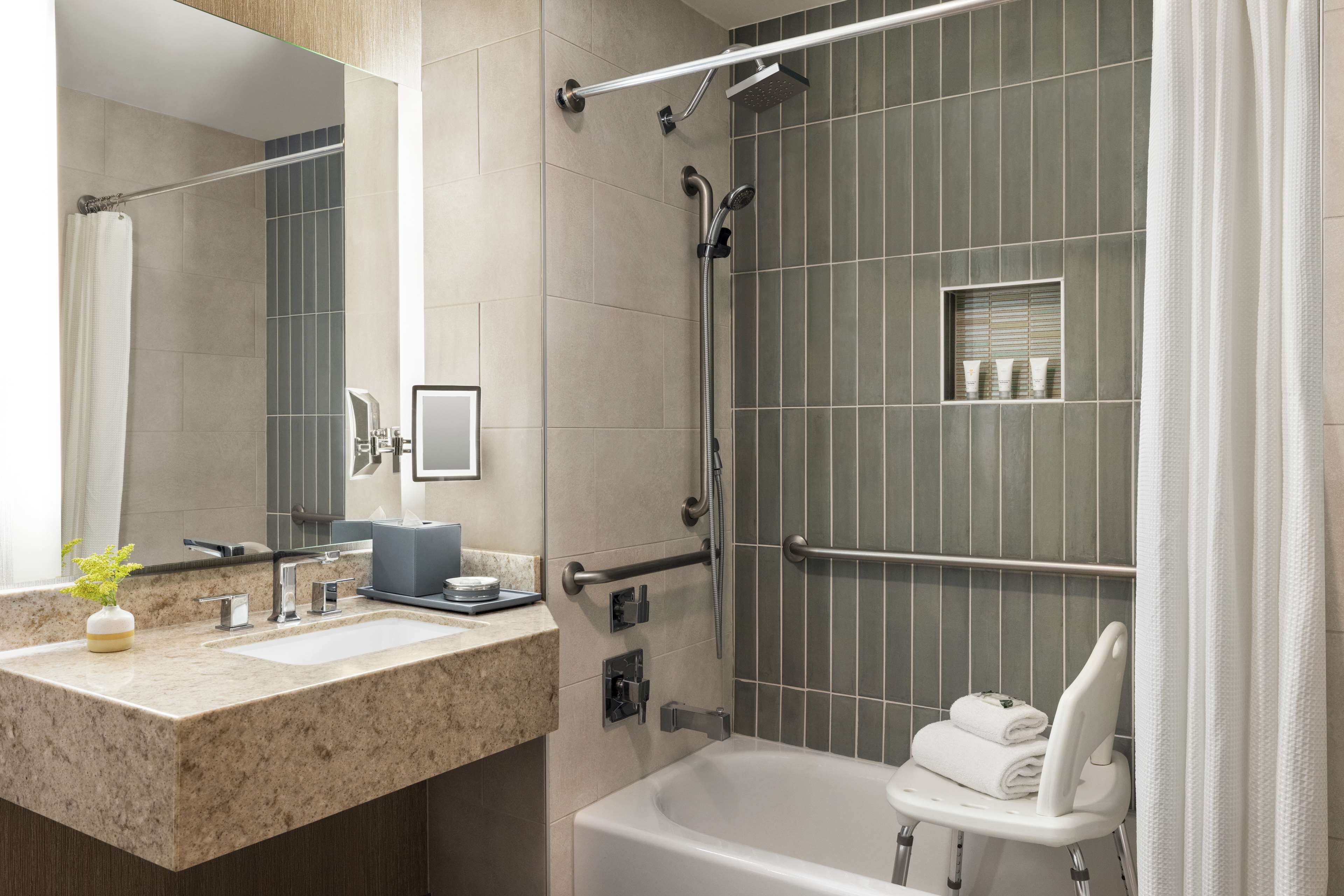 A modern bathroom with a bathtub, a shower area, and a vanity with a sink and mirror.