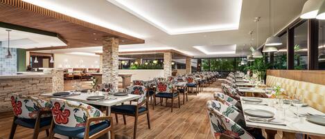 A spacious restaurant with high ceilings, wooden beams, and a long dining area with tables and chairs.