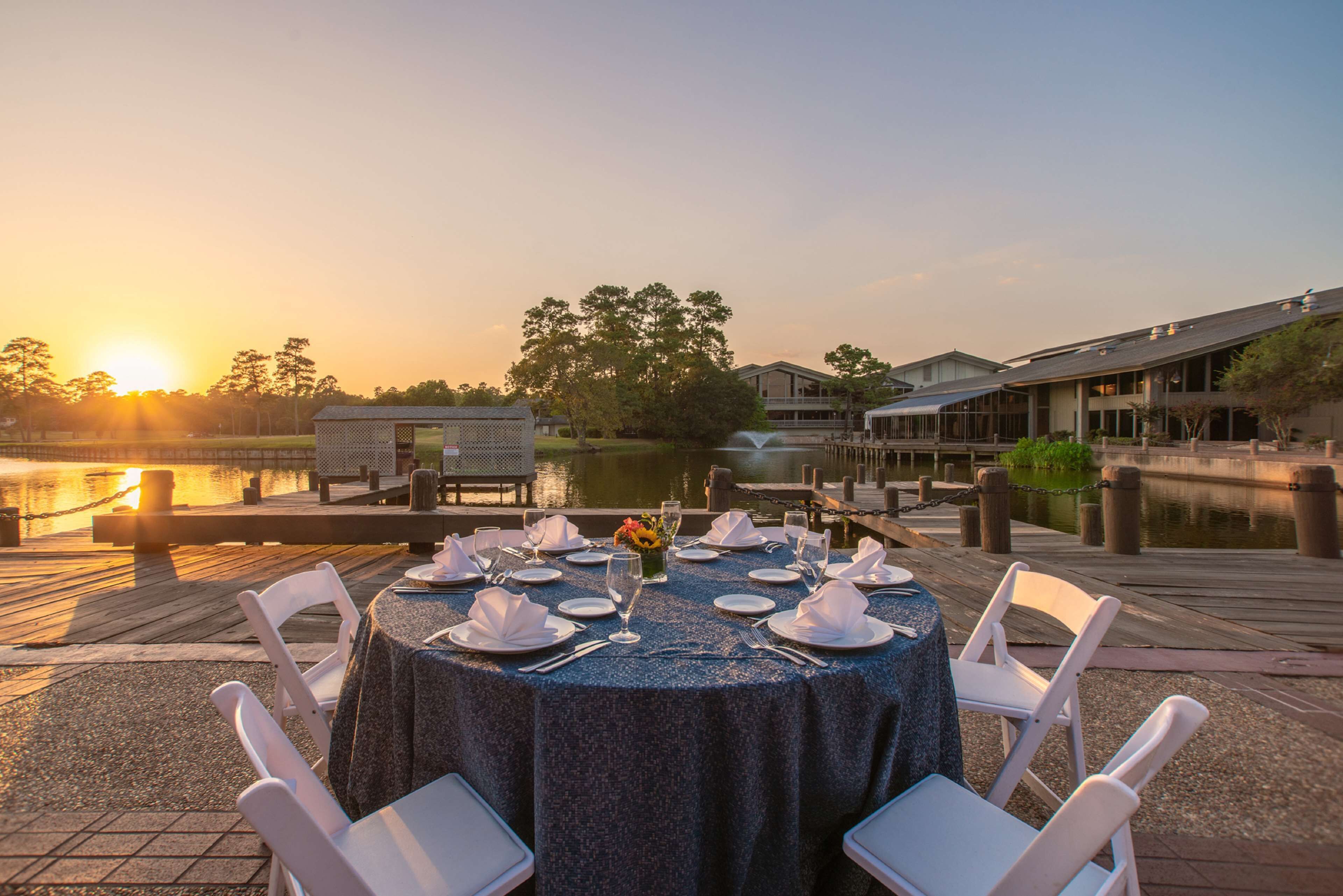 A table set for a meal with chairs, a view of a body of water, and buildings in the background.