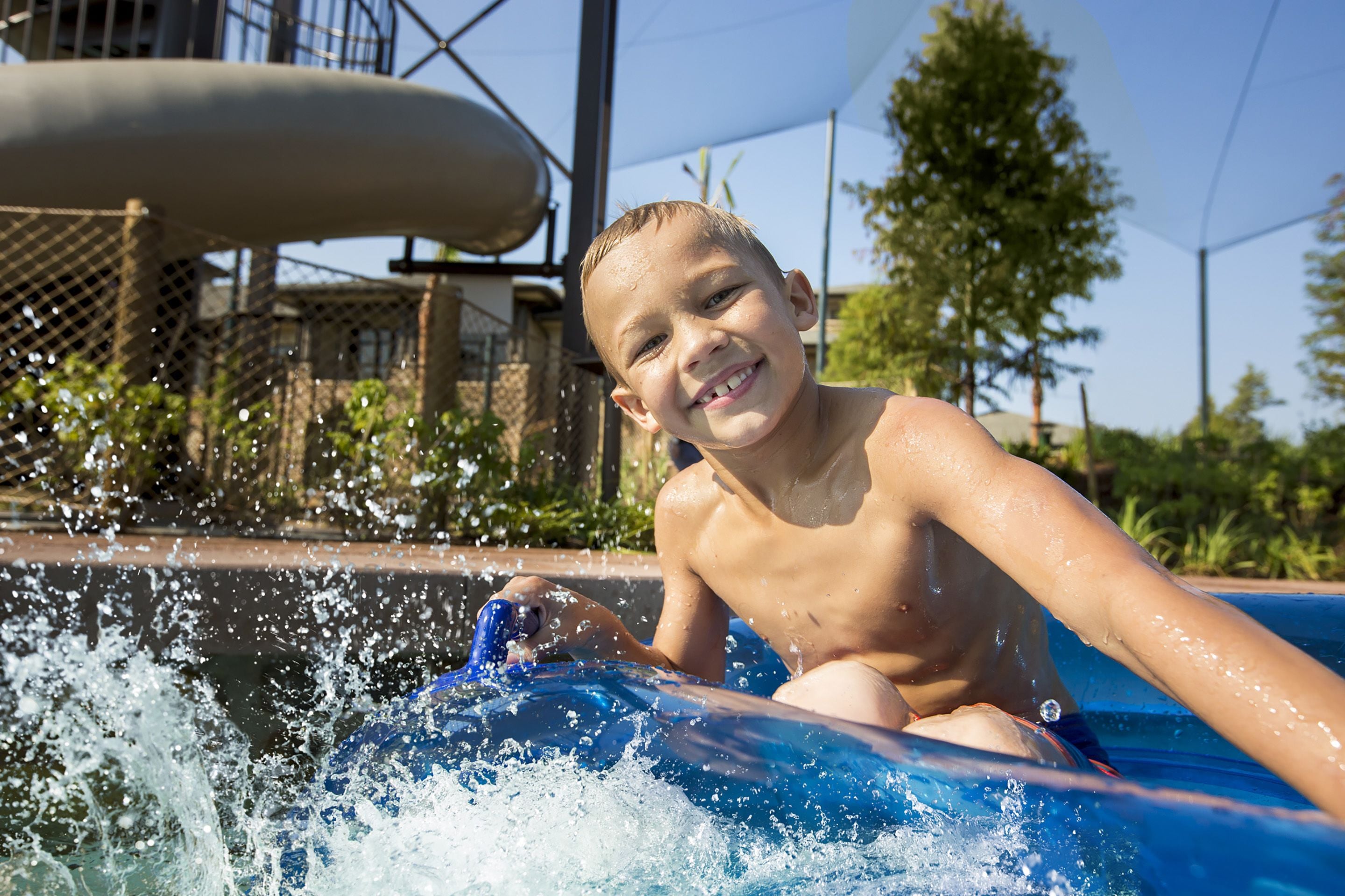 A person in a blue inflatable pool with water splashing around.