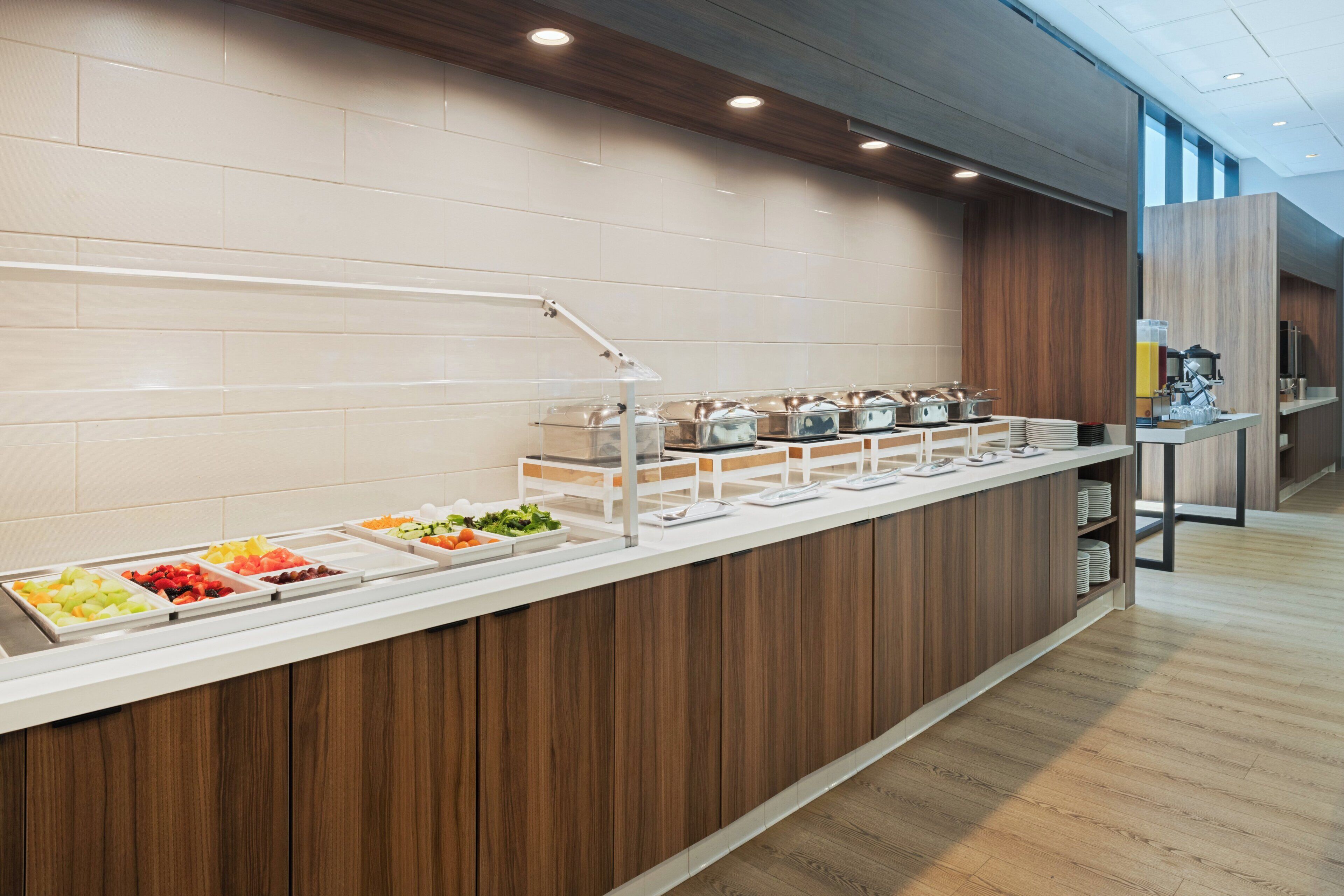 A buffet area with various food options, a coffee station, and a modern design with wooden accents.