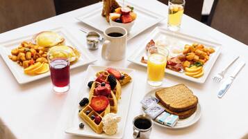 A breakfast table with various dishes including waffles, toast, and fruit.
