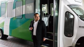Un hombre con traje baja de un autobús verde y blanco con un cartel de "Holiday Inn".