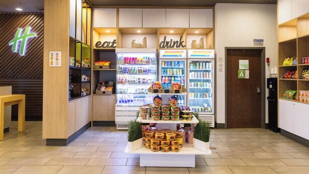 A modern convenience store with refrigerated sections labeled 'eat' and 'drink', and a display of packaged goods in the center. - Holiday Inn Los Angeles Gateway - Torrance by IHG (Torrance)