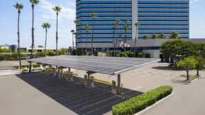 A Holiday Inn hotel with a parking lot featuring solar panels and palm trees. - Holiday Inn Los Angeles Gateway - Torrance by IHG (Torrance)