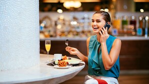 A person seated at a table with a glass of champagne, a plate with food, and a bottle of water. - Barceló México Reforma (Mexico City)