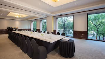 Un salón de conferencias con una larga mesa, sillas y un proyector.
