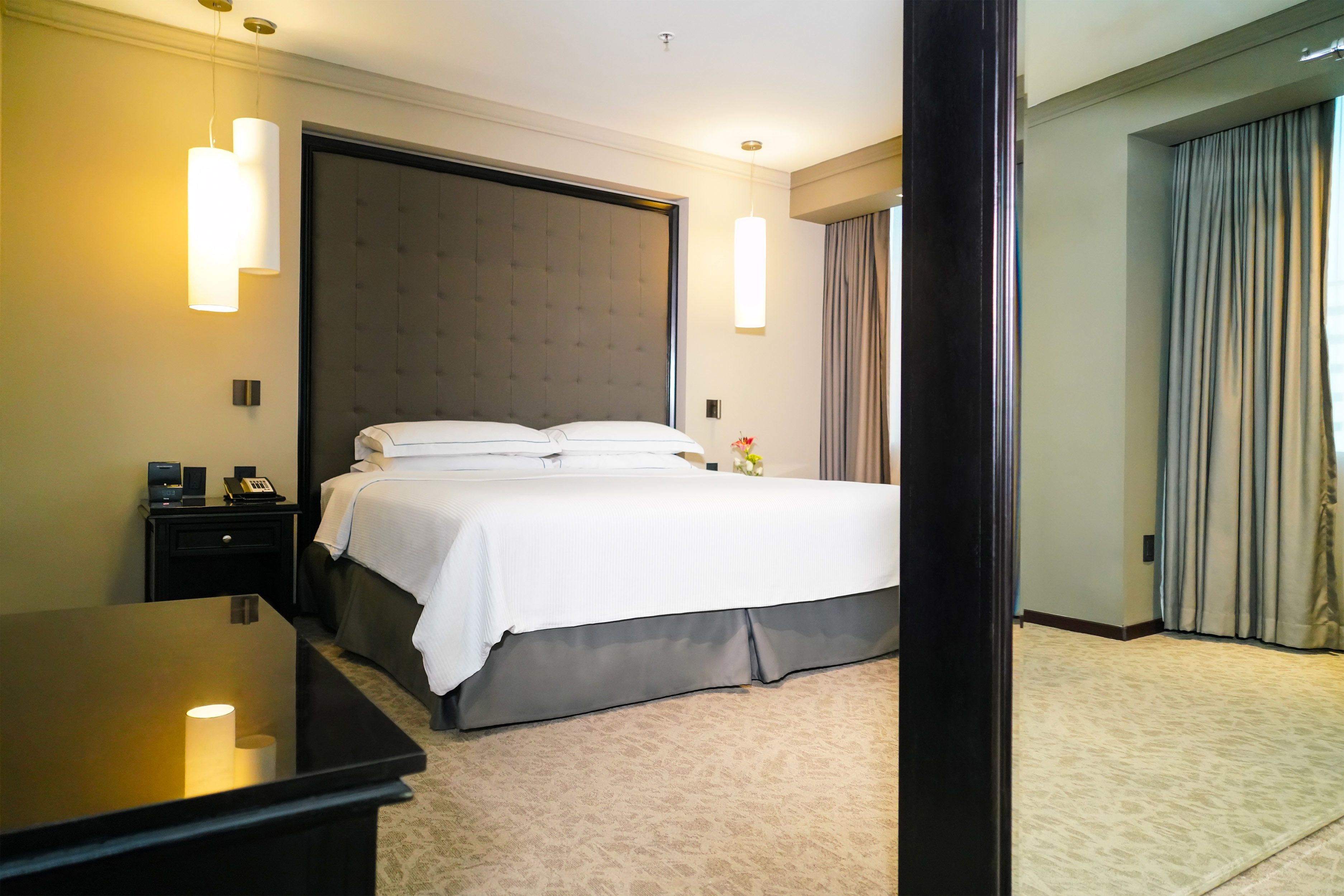 Habitación de hotel con una cama grande, mesitas de noche, un escritorio y vistas al exterior.