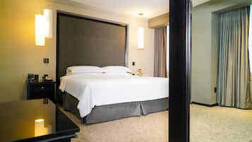 Habitación de hotel con una cama grande, mesitas de noche, un escritorio y vistas al exterior.
