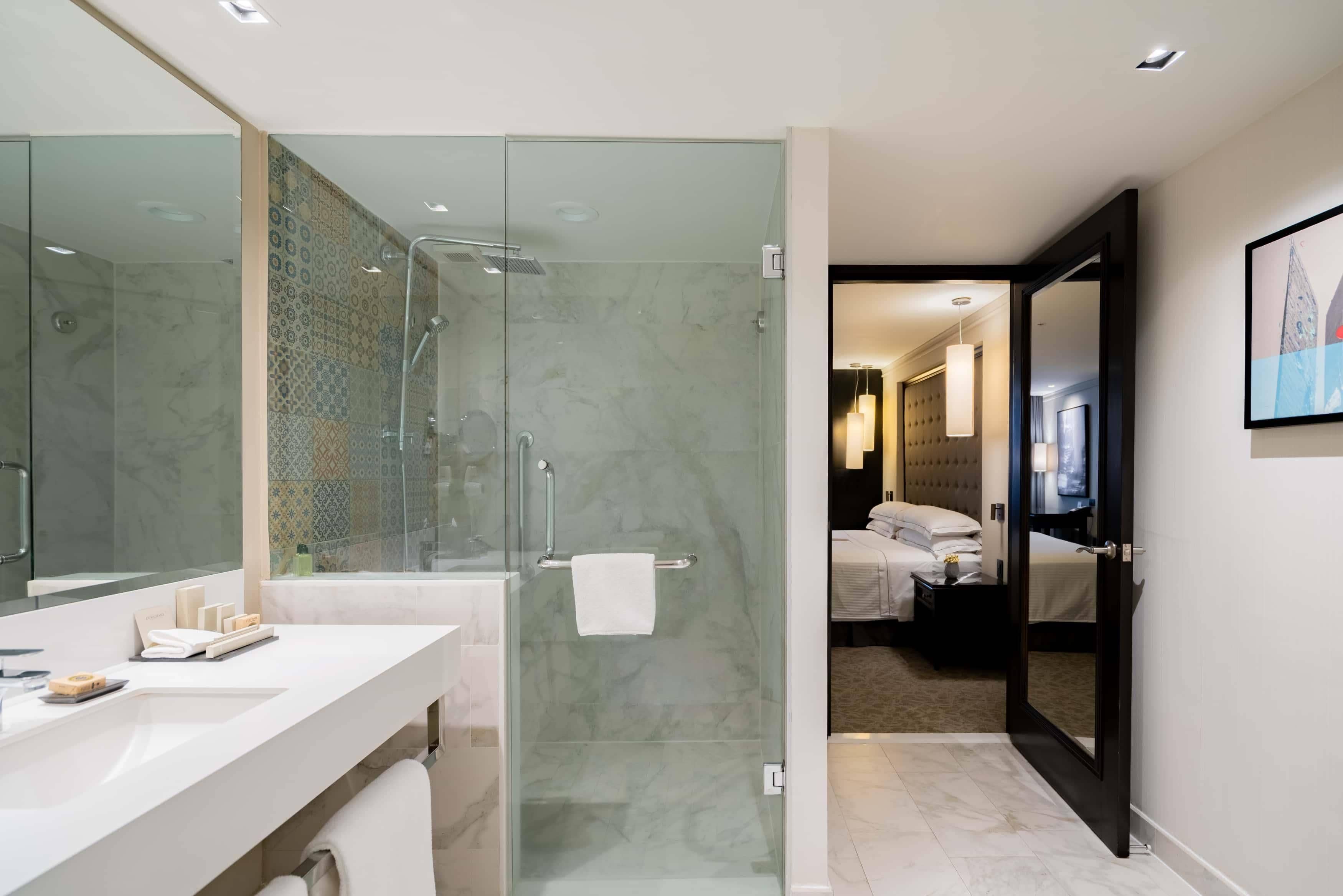 Un baño moderno con cabina de ducha de vidrio, tocador blanco y un espejo grande.