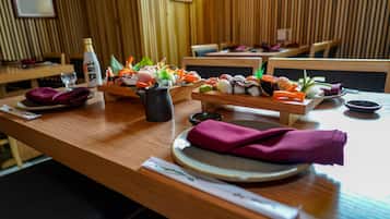 A restaurant interior with wooden paneling, sushi platters, a bottle, and a teapot on the table.