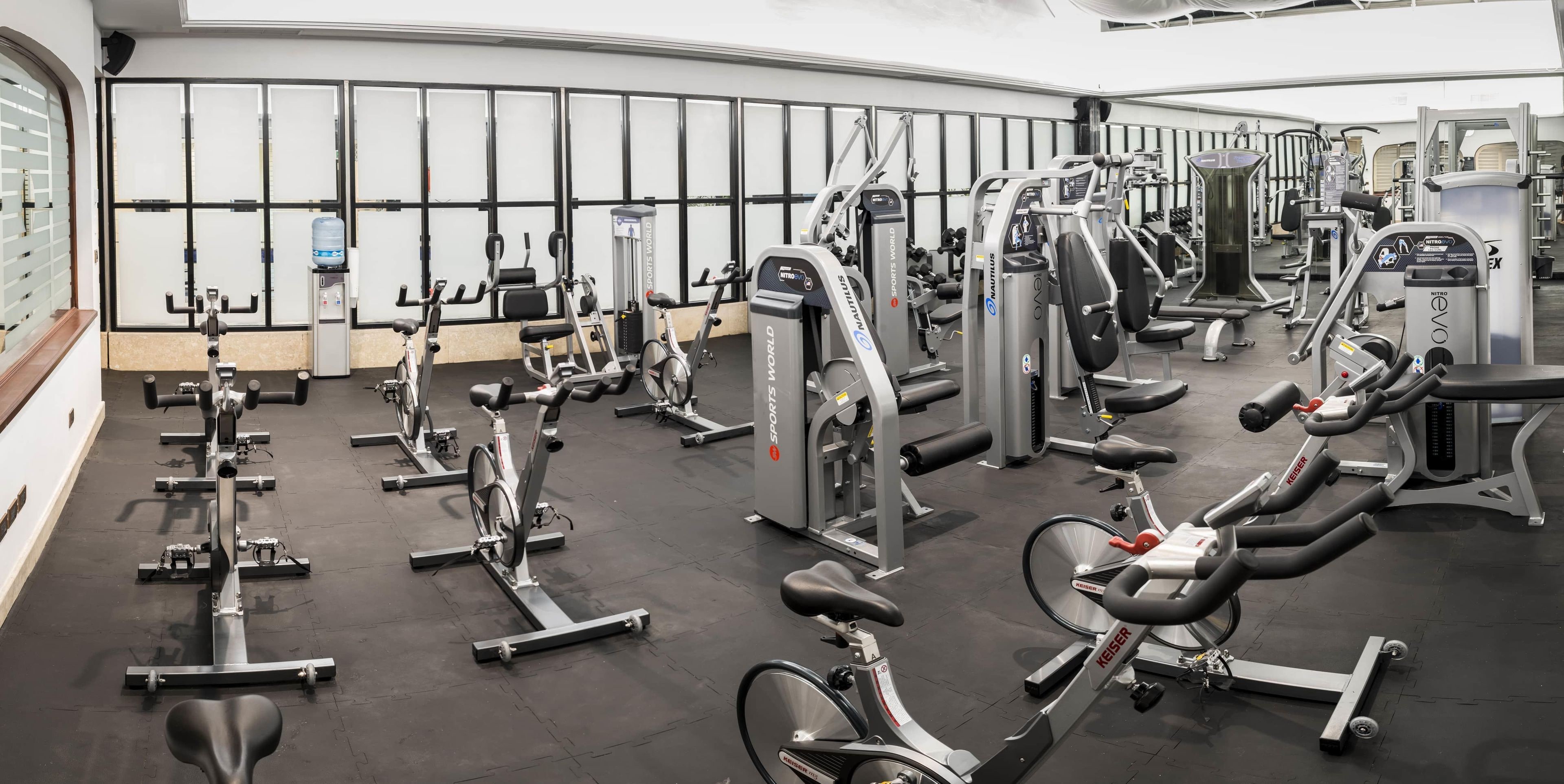 Une salle de sport équipée de divers appareils d’exercice, notamment des tapis de course, des vélos d’appartement et des appareils de musculation.