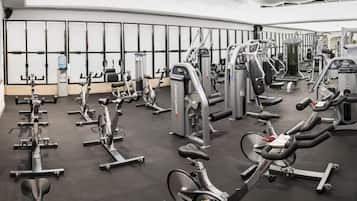 Une salle de sport équipée de divers appareils d’exercice, notamment des tapis de course, des vélos d’appartement et des appareils de musculation.