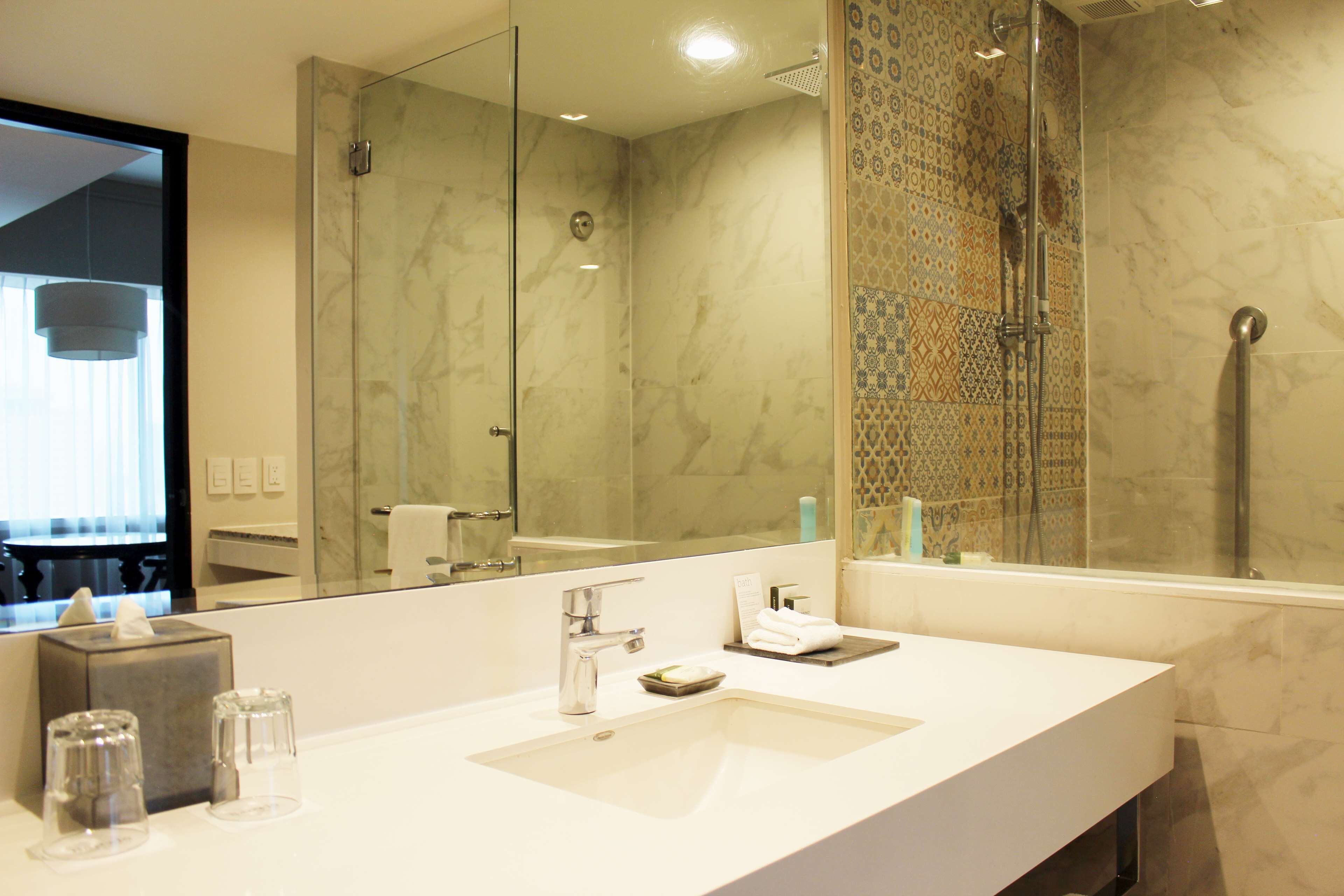 A modern bathroom with a large mirror, a sink, and a shower area.