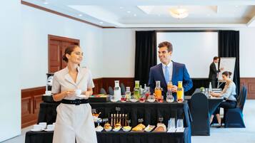 A conference room with a buffet table featuring various food items and beverages.