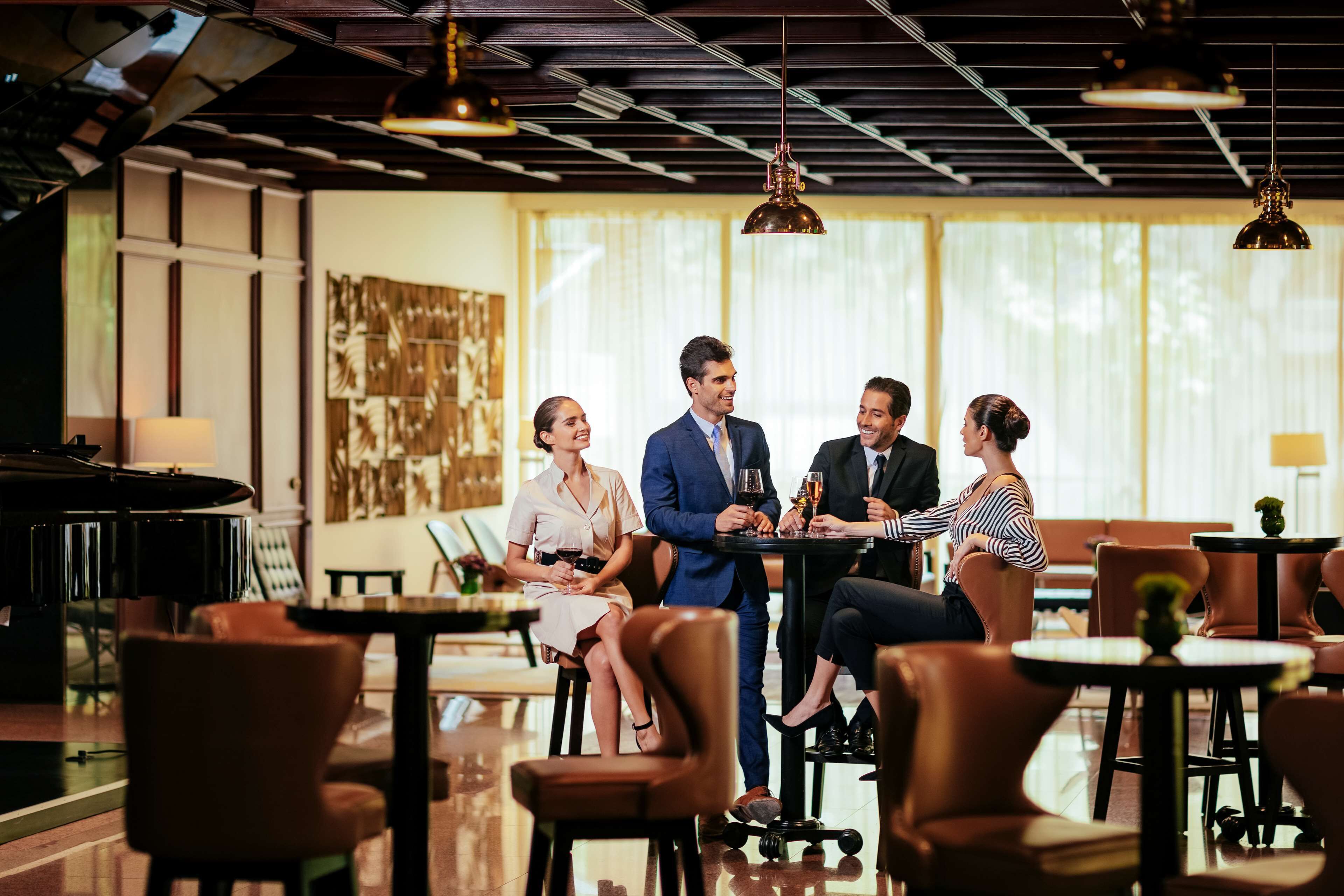 Uma sala de jantar moderna com piano, poltronas de couro e iluminação pendente.
