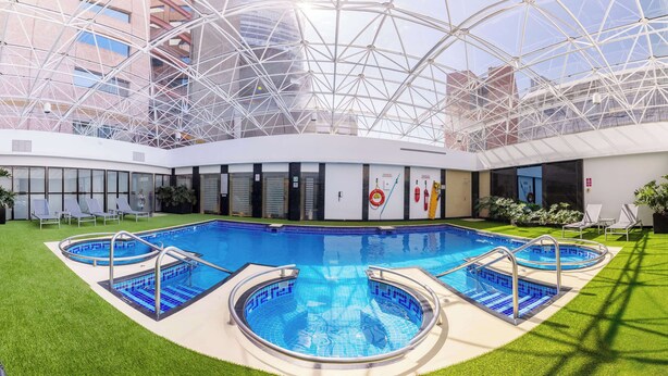 A swimming pool with two smaller pools and a glass ceiling structure.